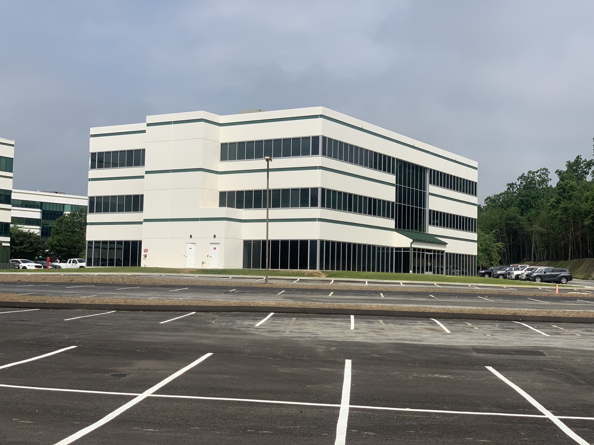 Completed three-story white office building with a newly paved parking lot