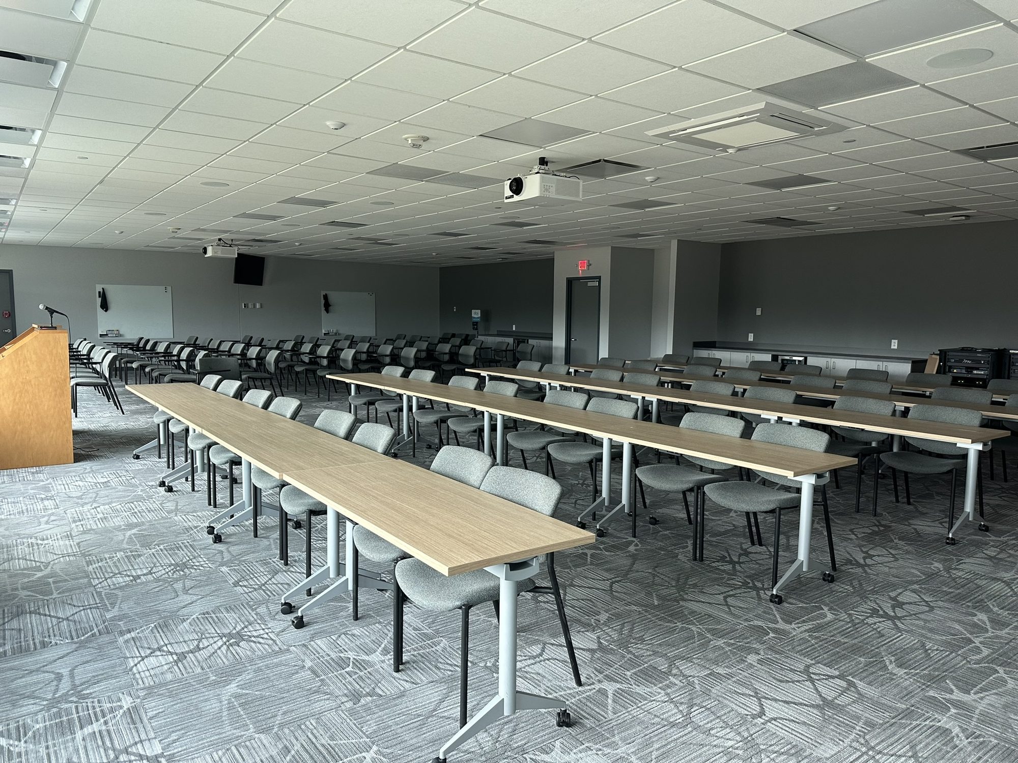 Finished conference room with rows of tables and chairs beneath a suspended ceiling